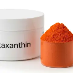 Sypka astaksantyna w pomarańczowym kolorze, obok białego pojemnika z napisem "Astaxanthin". Informacje o potencjalnych astaksantyna skutki uboczne mogą być na etykiecie.