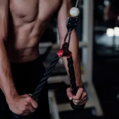 Mężczyzna wykonuje wyciskanie na triceps na siłowni, skupiając się na budowaniu masy mięśniowej ramion.