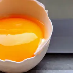 Rozbite jajko z płynnym żółtkiem i białkiem, gotowe do przygotowania posiłku bogatego w **egg protein**.