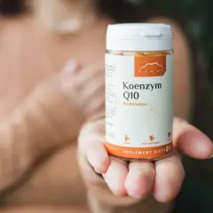 Dłoń trzyma opakowanie Koenzymu Q10. Czy to ubichinol czy ubichinon? Suplement diety dla zdrowia.
