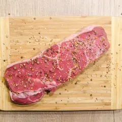 Surowy stek wołowy, przyprawiony pieprzem, gotowy na dietę carnivore.