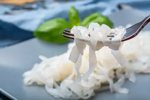 Nici z konjac na widelcu, obok liści bazylii. To zdrowa alternatywa dla tradycyjnego makaronu.