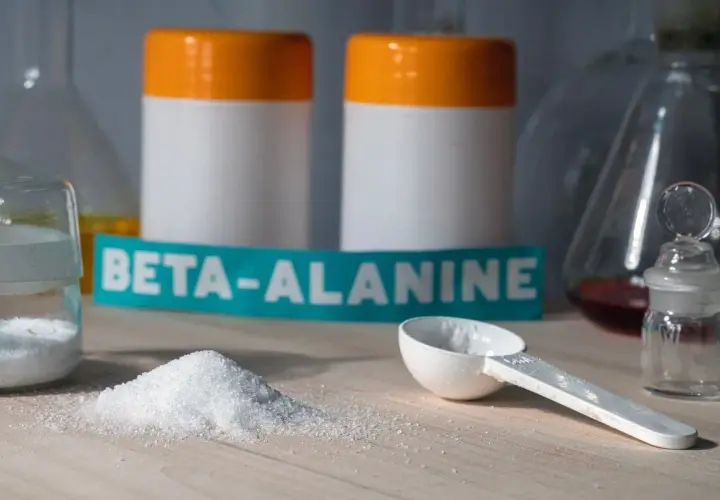 Biały proszek beta alaniny na blacie, gotowy do suplementacji. Może wywołać charakterystyczne mrowienie.