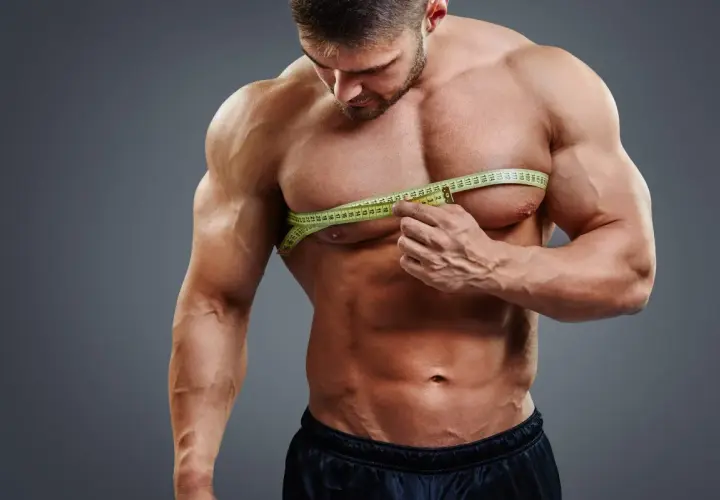Mięśniak mierzy obwód klatki piersiowej, przygotowując się do diety na masę 80 kg.