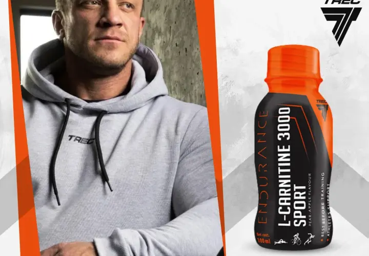 Mężczyzna w szarej bluzie z kapturem obok butelki L-Carnitine 3000 Extreme Shot o smaku gruszka-jabłko.