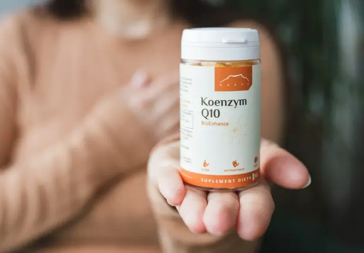 Dłoń trzyma opakowanie Koenzymu Q10. Czy to ubichinol czy ubichinon? Suplement diety dla zdrowia.