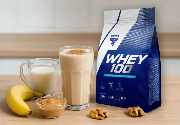 Bananowy koktajl z białkiem z wodą czy mlekiem? Obok opakowanie WHEY 100, masło orzechowe i orzechy.