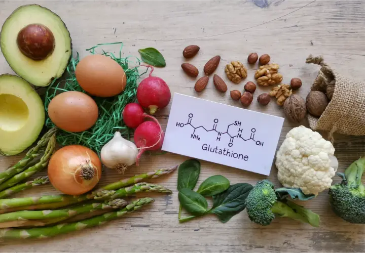 Zdjęcie przedstawia składniki odżywcze, które mogą wspierać produkcję glutationu: awokado, jajka, orzechy, brokuły, kalafior, szpinak, czosnek, cebulę, szparagi i rzodkiewkę.