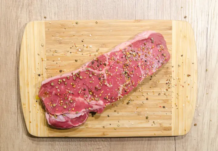Surowy stek wołowy, przyprawiony pieprzem, gotowy na dietę carnivore.