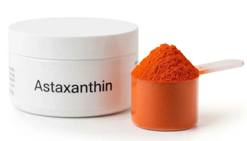 Sypka astaksantyna w pomarańczowym kolorze, obok białego pojemnika z napisem "Astaxanthin". Informacje o potencjalnych astaksantyna skutki uboczne mogą być na etykiecie.