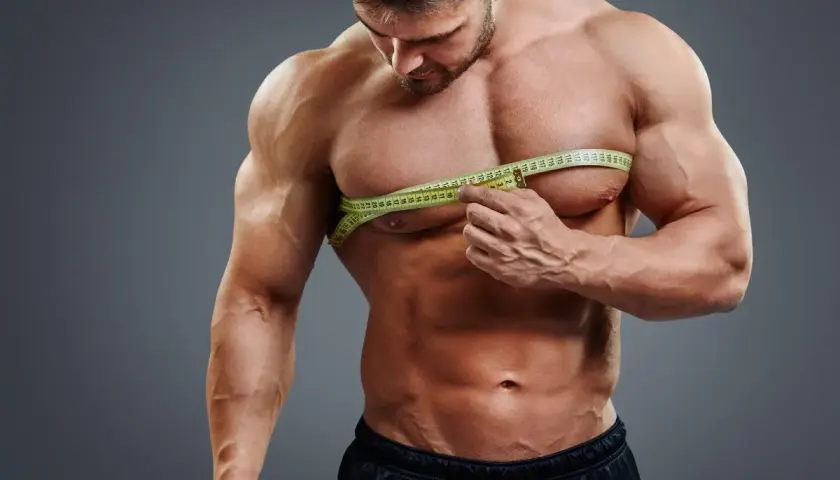 Mięśniak mierzy obwód klatki piersiowej, przygotowując się do diety na masę 80 kg.