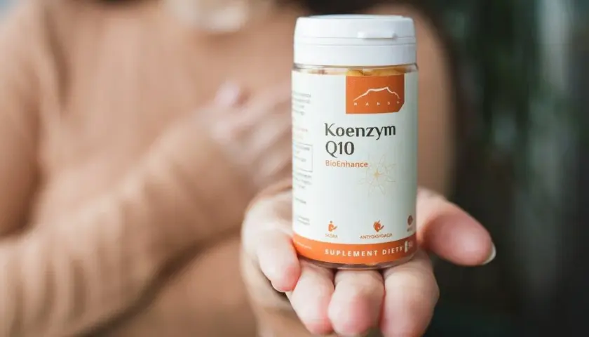 Dłoń trzyma opakowanie Koenzymu Q10. Czy to ubichinol czy ubichinon? Suplement diety dla zdrowia.