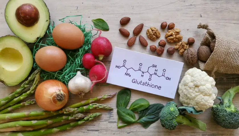 Zdjęcie przedstawia składniki odżywcze, które mogą wspierać produkcję glutationu: awokado, jajka, orzechy, brokuły, kalafior, szpinak, czosnek, cebulę, szparagi i rzodkiewkę.