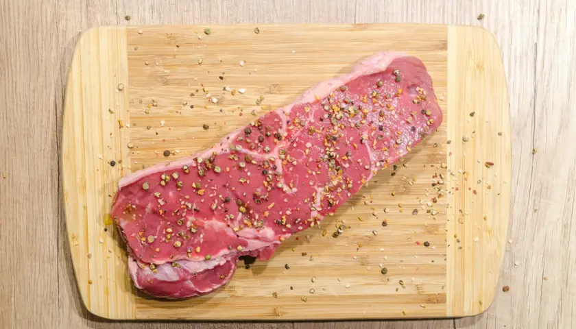 Surowy stek wołowy, przyprawiony pieprzem, gotowy na dietę carnivore.