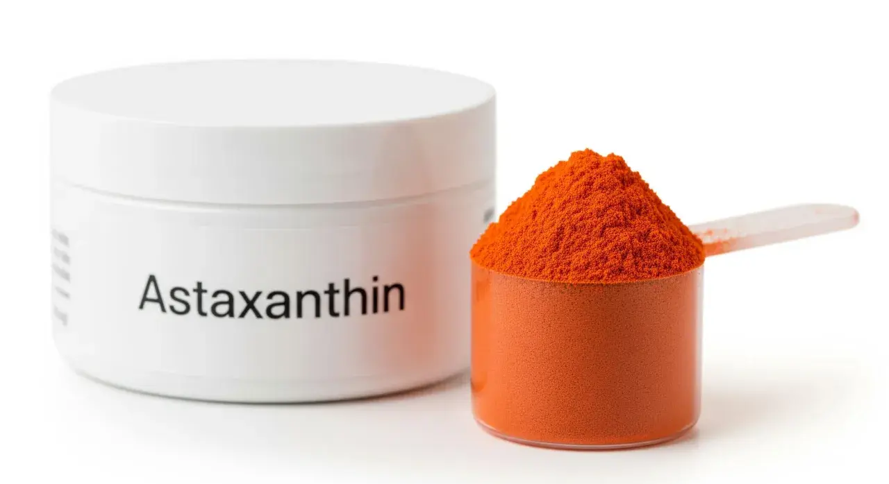 Sypka astaksantyna w pomarańczowym kolorze, obok białego pojemnika z napisem "Astaxanthin". Informacje o potencjalnych astaksantyna skutki uboczne mogą być na etykiecie.
