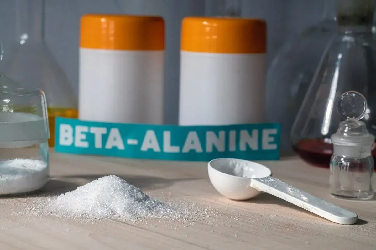 Biały proszek beta alaniny na blacie, gotowy do suplementacji. Może wywołać charakterystyczne mrowienie.