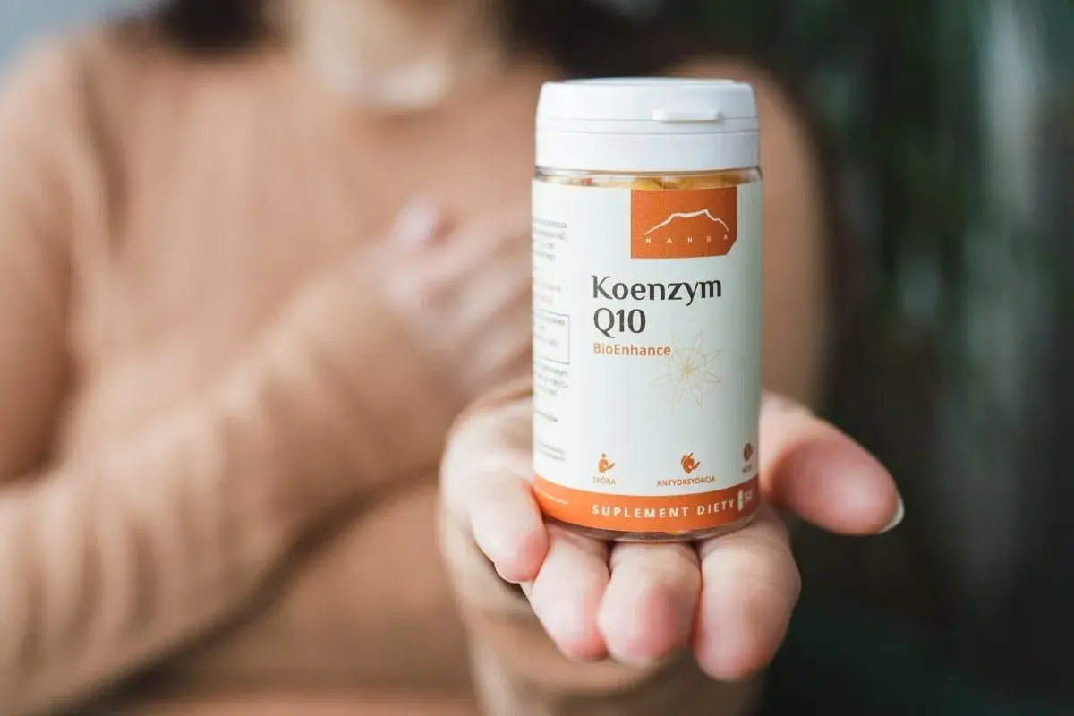 Dłoń trzyma opakowanie Koenzymu Q10. Czy to ubichinol czy ubichinon? Suplement diety dla zdrowia.
