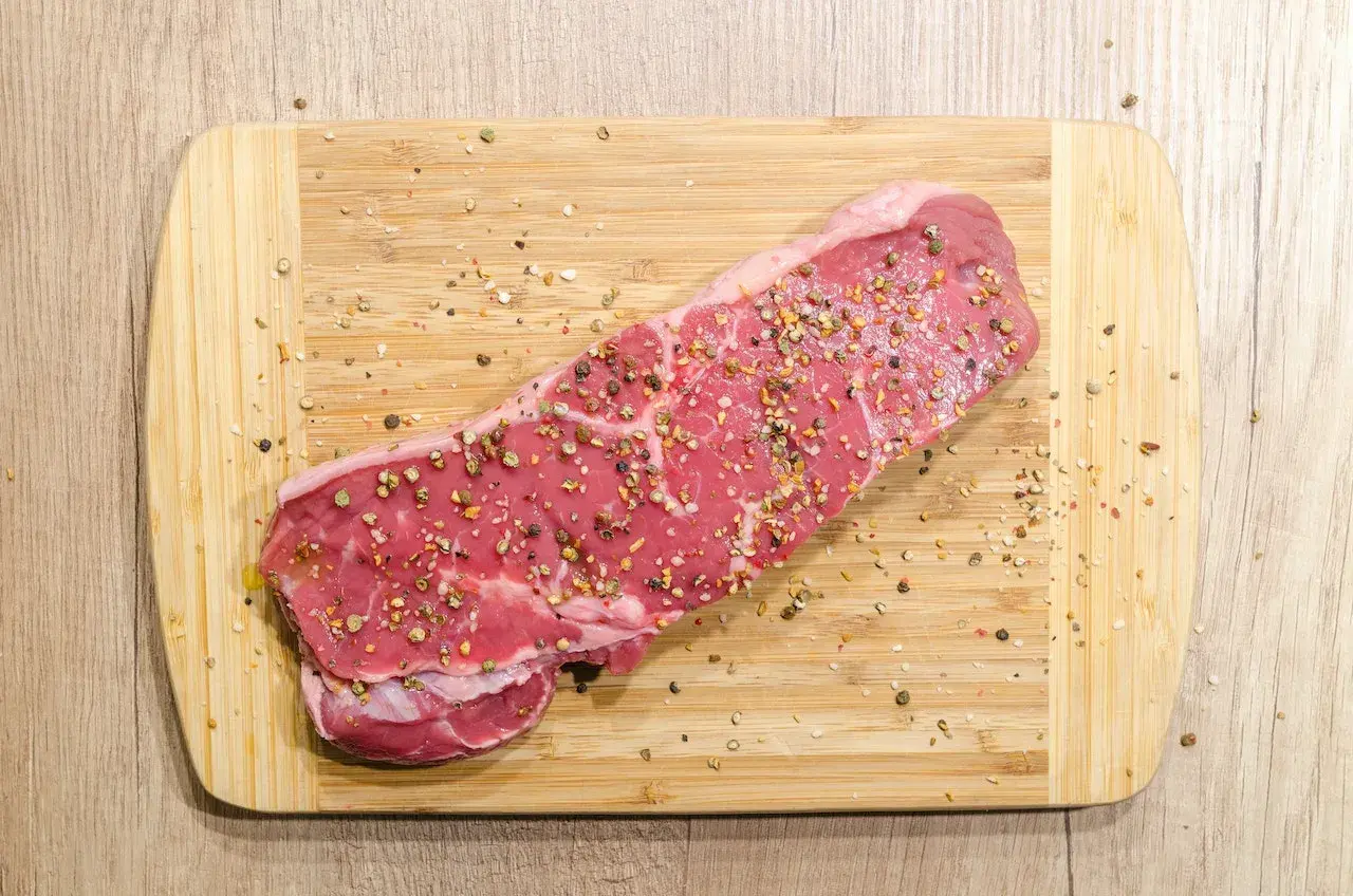 Surowy stek wołowy, przyprawiony pieprzem, gotowy na dietę carnivore.