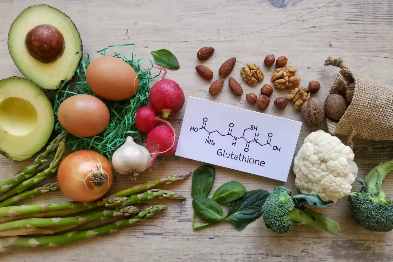 Zdjęcie przedstawia składniki odżywcze, kt&oacute;re mogą wspierać produkcję glutationu: awokado, jajka, orzechy, brokuły, kalafior, szpinak, czosnek, cebulę, szparagi i rzodkiewkę.